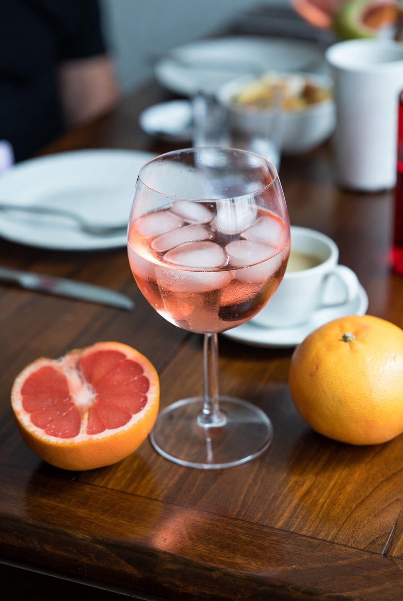 Schnappschuss von rosa Gin auf einem unordentlichen Holztisch